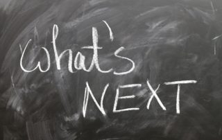 "What's next" scrawled on a blackboard with white chalk